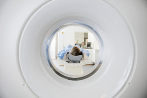 Woman Undergoing CT Scan While Doctor's Using Computers